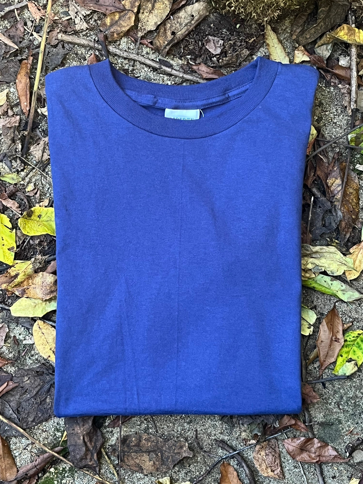 Organic cotton Blue t-shirt on a stone surface with leaves